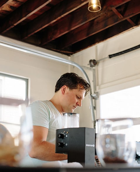 Mike grinds coffee.