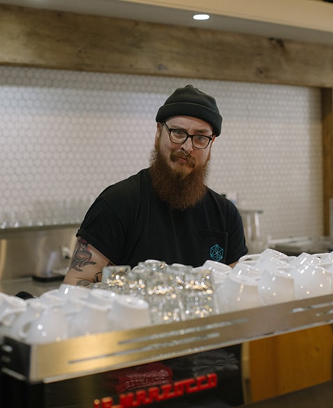 He poses behind the espresso machine.