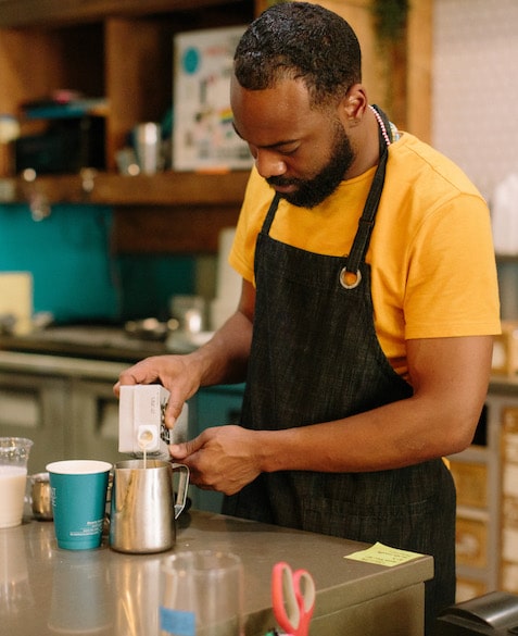 El Strickland pours milk into a coffee