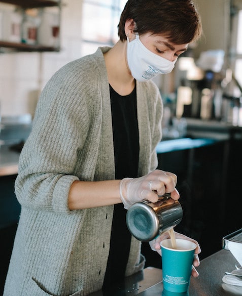 MG Batts pours coffee into a Blueprint Coffee to go cup