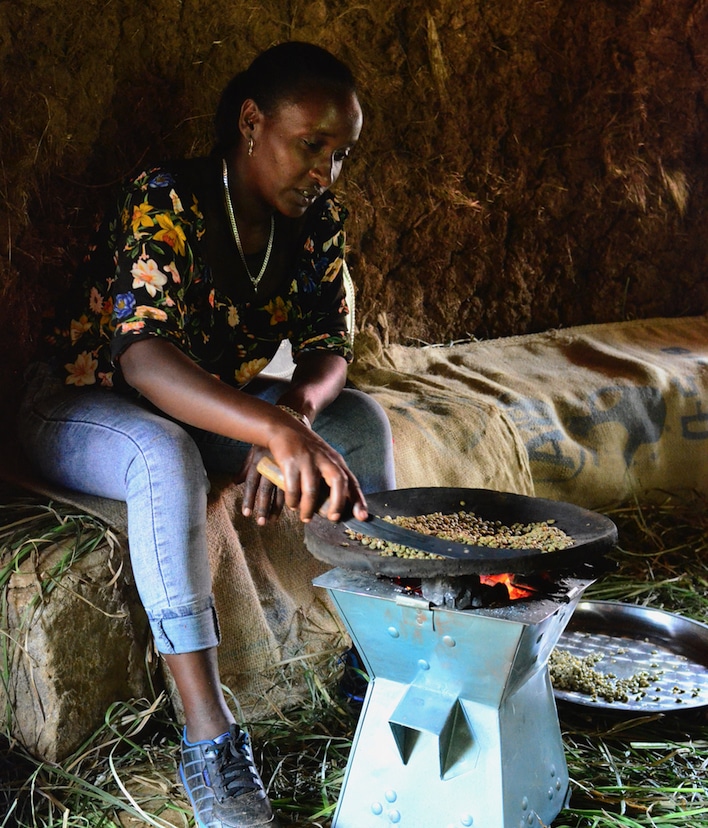 A person roasts coffee beans over a fire.
