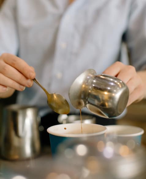 Mac pours syrup into a Blueprint Coffee to go cup
